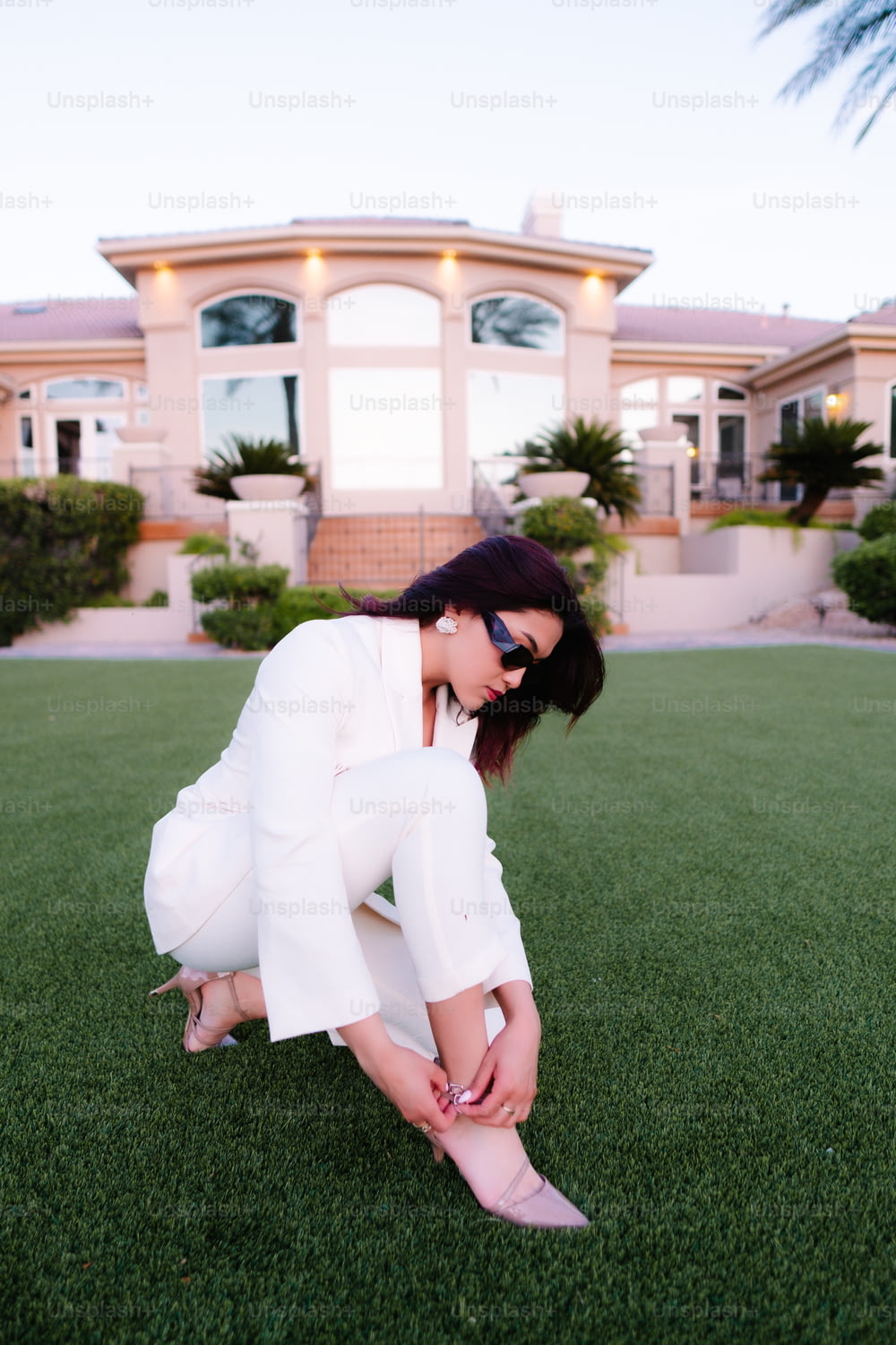 uma mulher em um terno branco ajoelhado na grama
