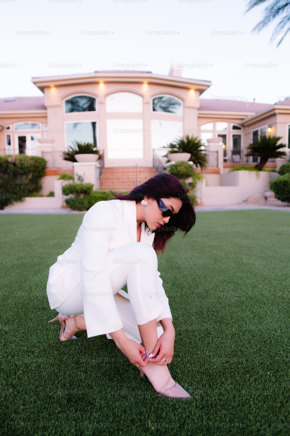 a woman in a white suit kneeling on the grass