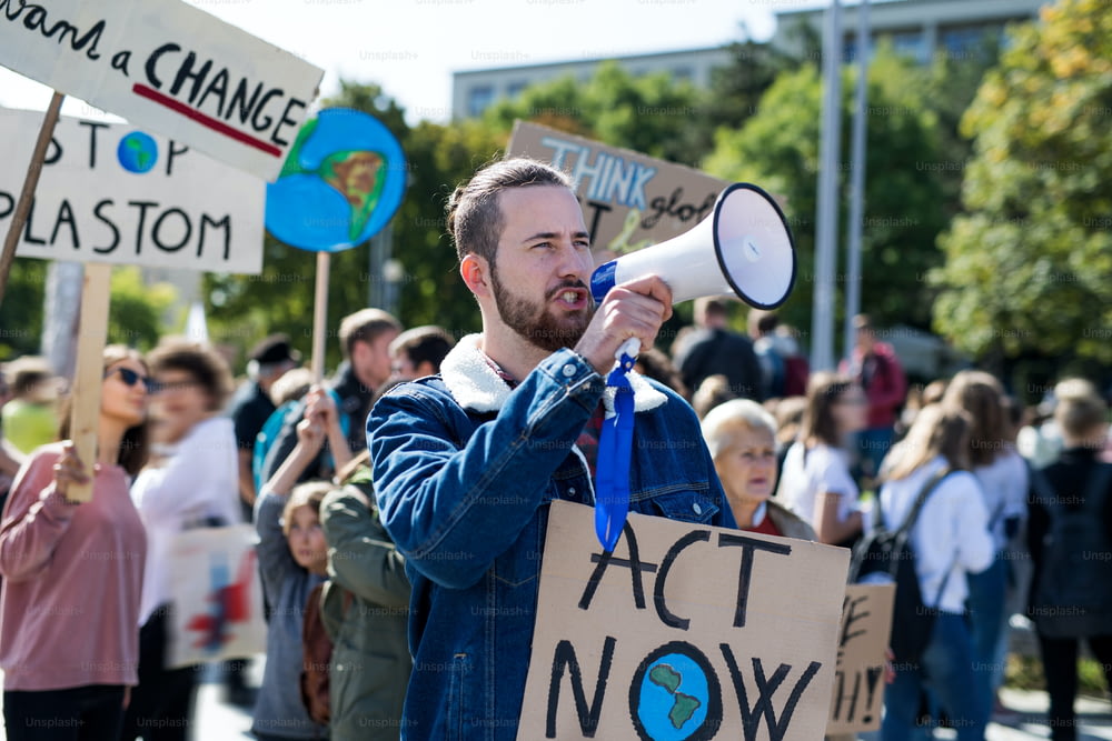 Un hombre con pancartas y amplificador en huelga mundial por el cambio climático, gritando.