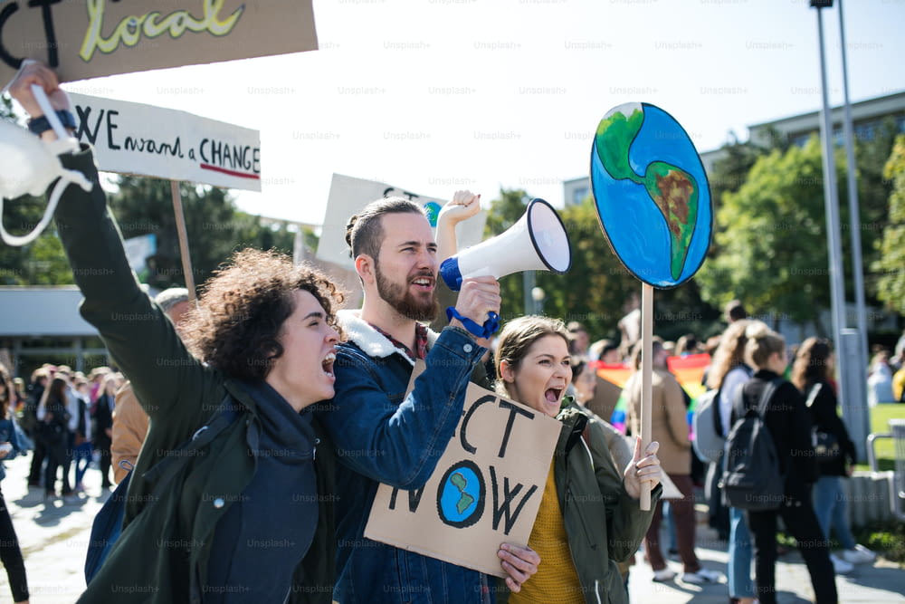 Personas con pancartas y amplificadores en una huelga global por el cambio climático, gritando.