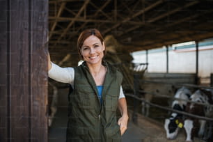 Lavoratrice in piedi nella fattoria del diario, guardando la telecamera. Industria agricola.