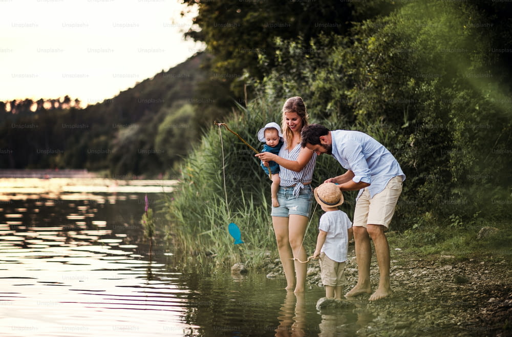 A young family with two toddler children spending time outdoors by the river in summer.