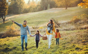 A happy young family with two small children walking in autumn nature.