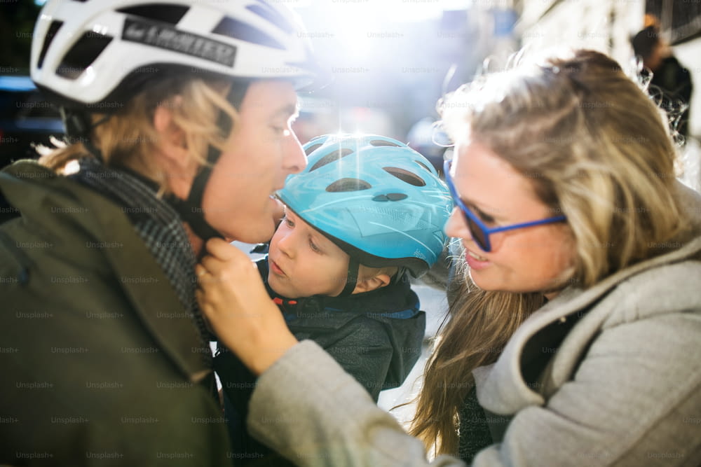 자전거 헬멧을 쓴 작은 소년과 도시의 야외에서 젊은 부모.
