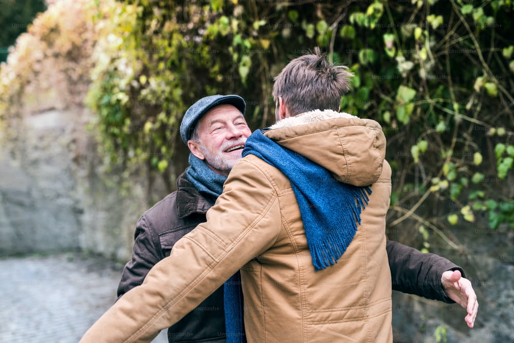 Il padre anziano e il suo giovane figlio durante una passeggiata in città, abbracciati.