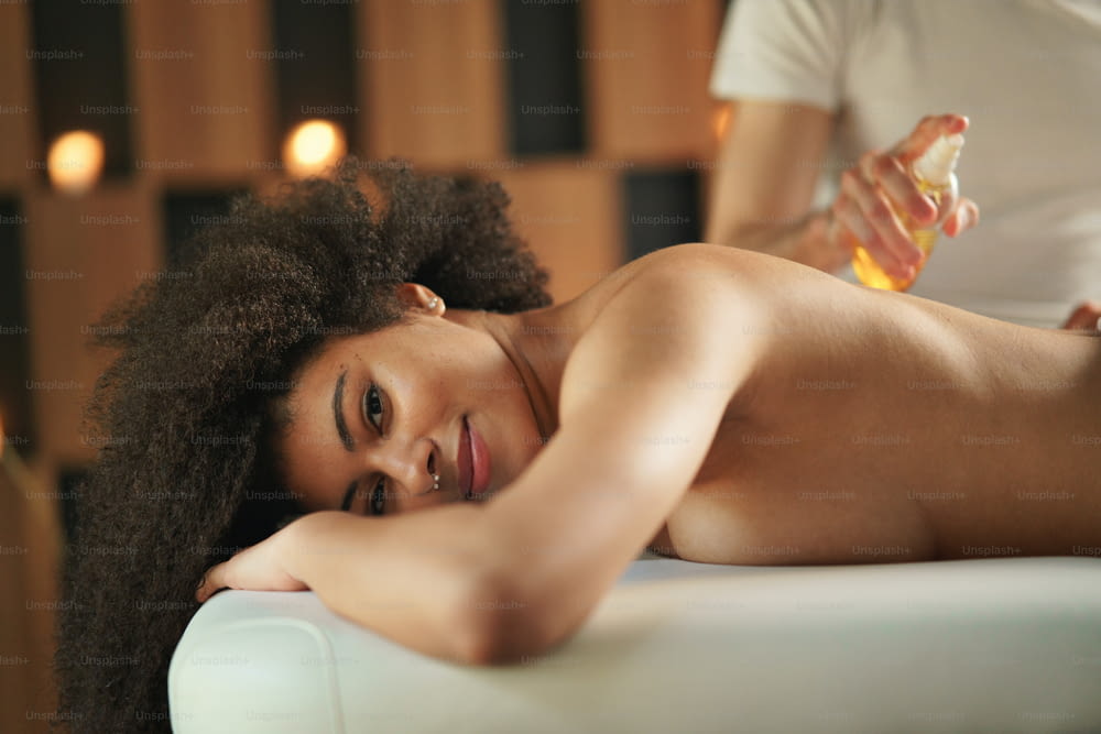 Young woman having relaxing back massage at the spa, looking at camera.