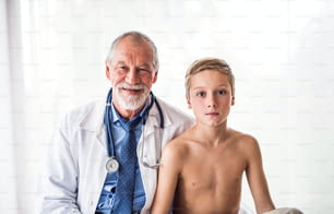 Retrato de un médico de alto nivel con estetoscopio y un niño pequeño en una oficina.