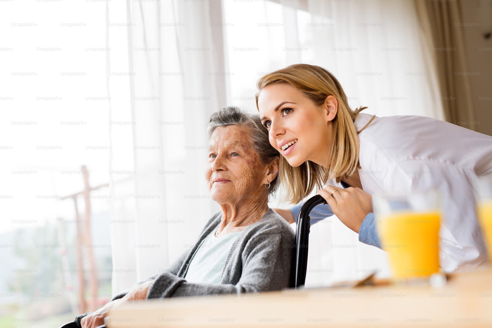 Visitatore sanitario e una donna anziana durante la visita domiciliare. Un'infermiera che parla con una donna anziana su una sedia a rotelle.