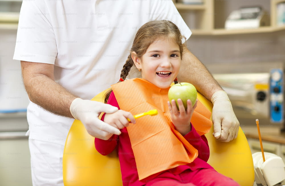 Dentist is showing the technique of teeth cleaning to a little girl