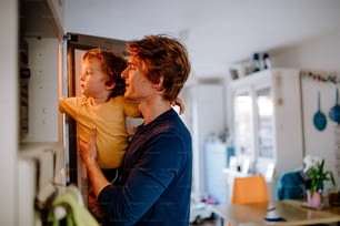 Un jeune père avec un fils en bas âge passant du temps dans une cuisine à la maison.