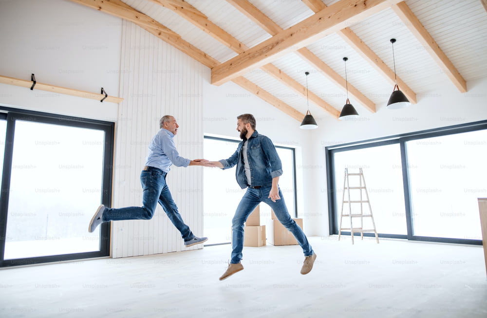 A cheerful mature man jumping with his senior father in new house, a new home concept.