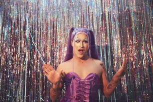 a woman in a purple dress standing in front of a curtain