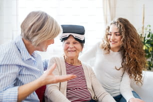 A teenage girl, her mother and grandmother with VR goggles at home. Family and generations concept.