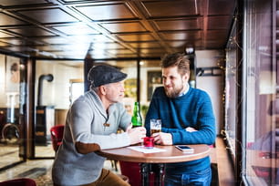 Pai sênior e seu filho pequeno bebendo cerveja em um pub.