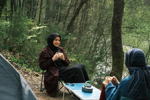 Eine Frau im Hijab sitzt an einem Tisch mit einer Tasse Kaffee