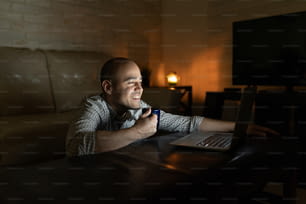 Portrait of a good looking man relaxing and watching a tv show or movie on a laptop computer at night
