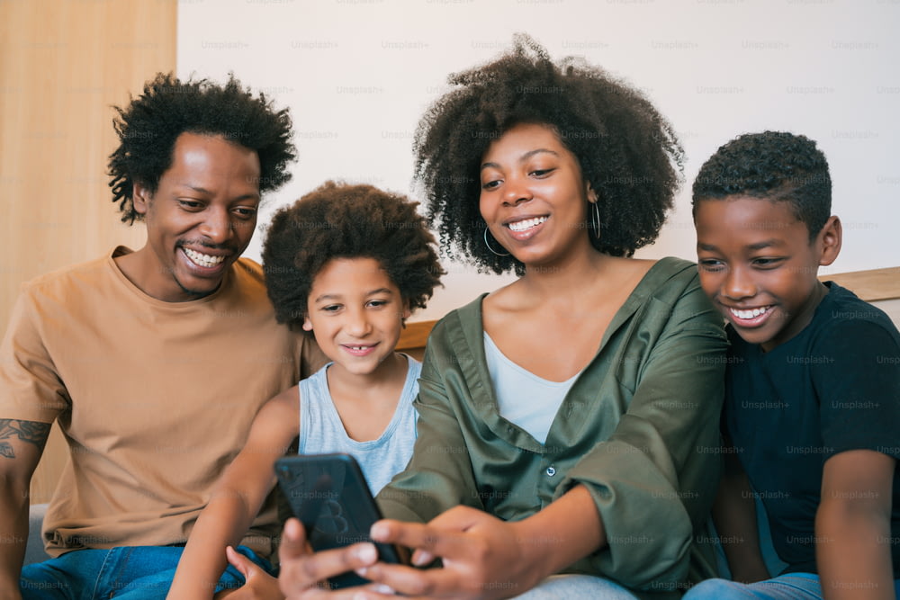 Portrait d’une famille afro-américaine prenant un selfie avec un téléphone portable à la maison. Concept de famille et de style de vie.