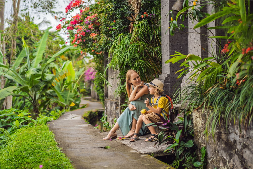 Mother and son tourists in Bali walks along the narrow cozy streets of Ubud. Bali is a popular tourist destination. Travel to Bali concept. Traveling with children concept.