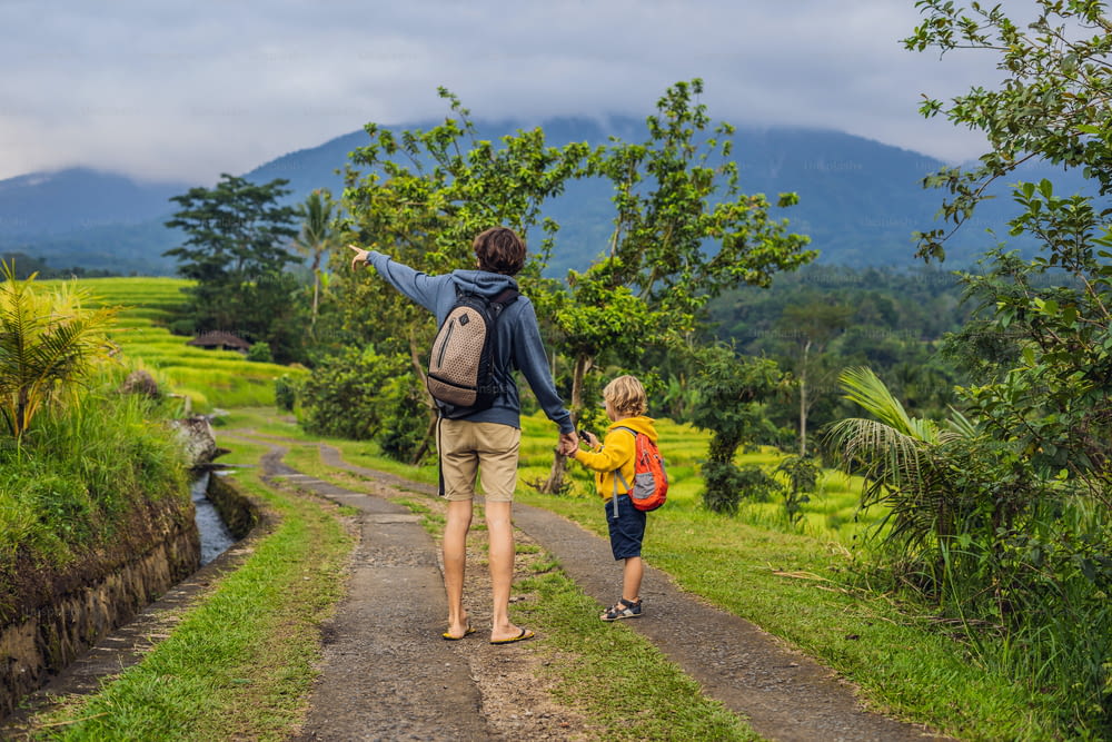 아빠와 아들은 인도네시아 발리의 유명한 화산을 배경으로 아름다운 Jatiluwih 라이스 테라스를 여행합니다. 아이들과 함께 여행하는 개념.