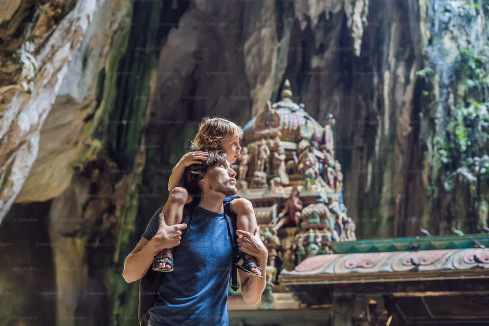 マレーシアのクアラルンプール近郊のバトゥ洞窟の背景にいる父と息子。子供との旅行のコンセプト。