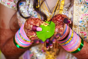 Indischer Bräutigam und Braut, der Mangalsutra oder Goldkette mit grünem Blatt in der Hand hält
