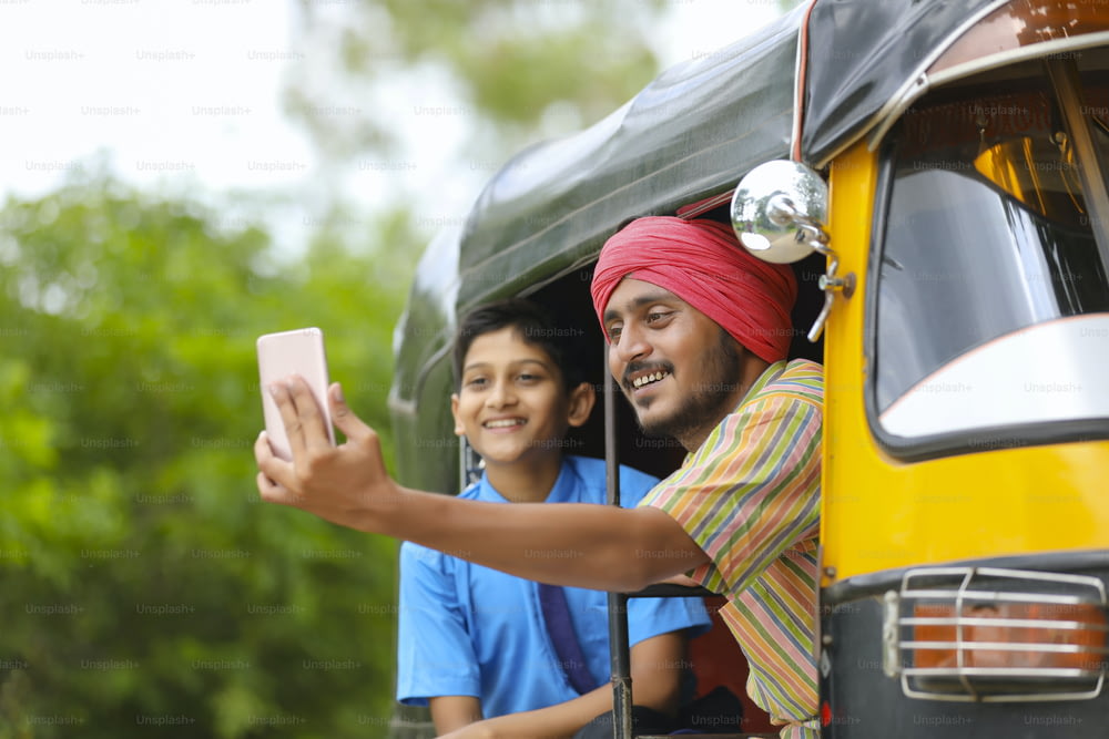 Indischer Auto-Rikscha- oder Tuk-Tuk-Fahrer macht Selfie mit seinem Schüler