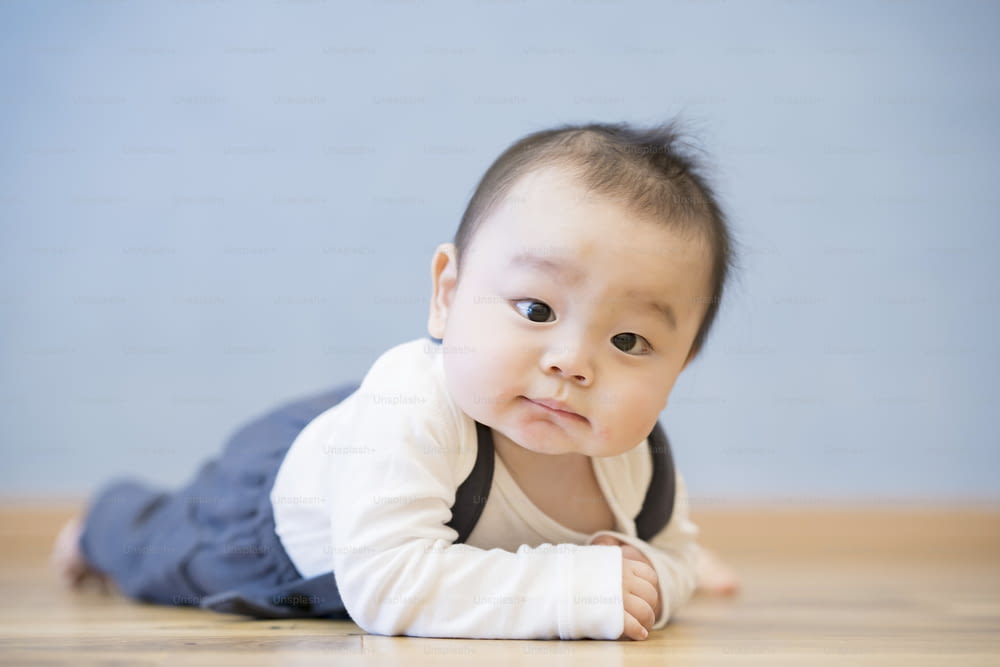 Bambino giapponese che striscia sul pavimento di legno nella stanza