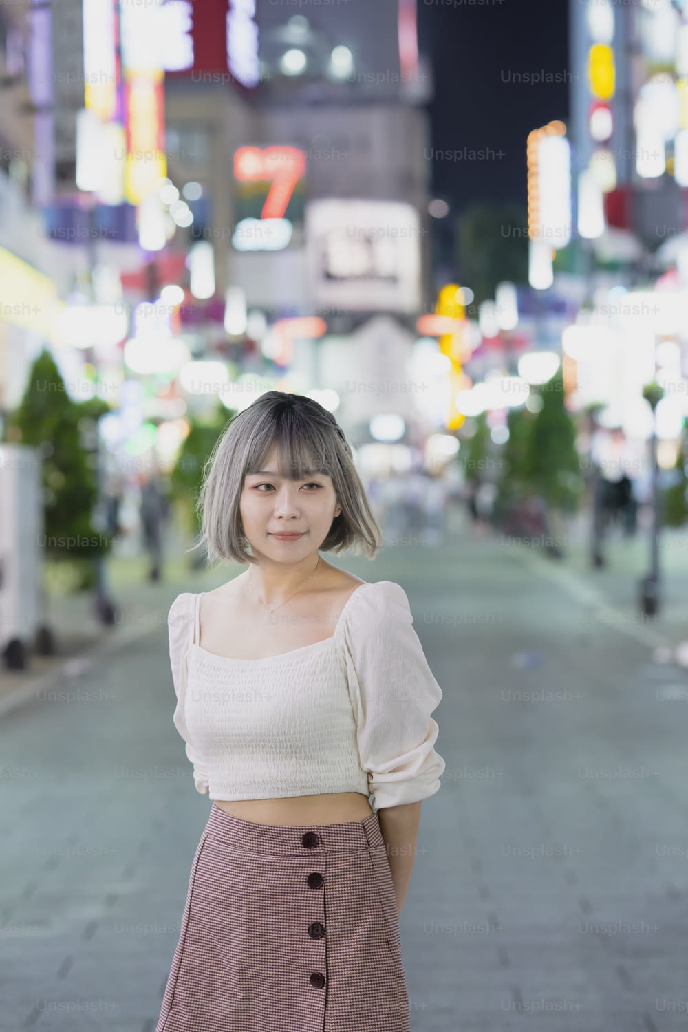 Junge Frau posiert nachts im leuchtenden Stadtbild von Tokio