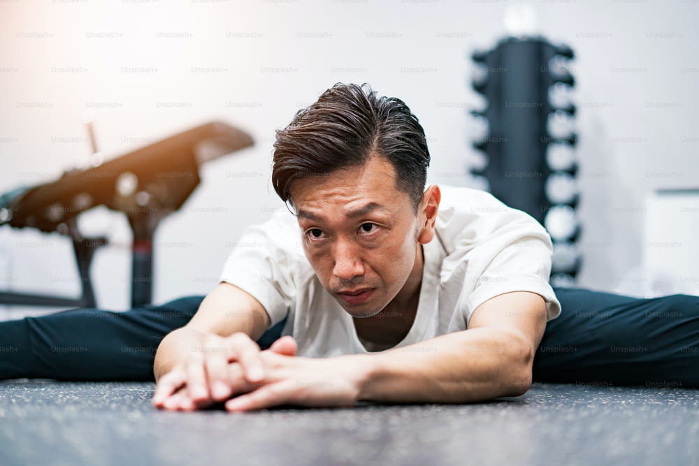 Middle-aged man doing stretching exercises in the gym