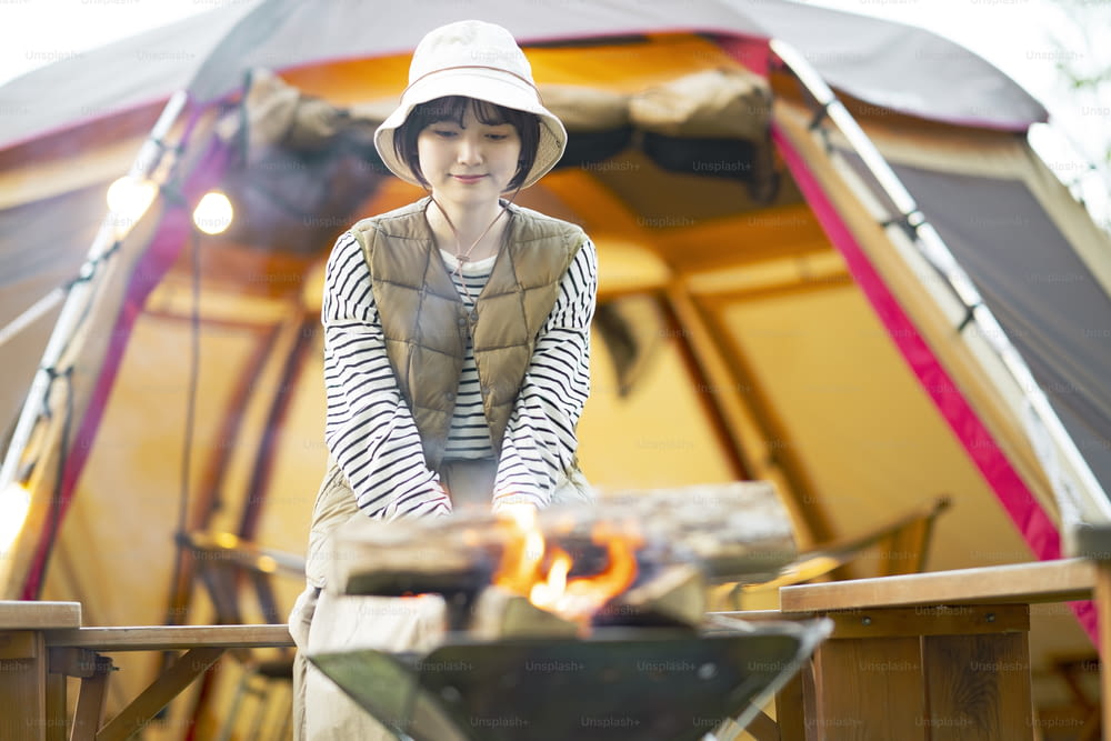 A woman enjoying a bonfire in front of tent
