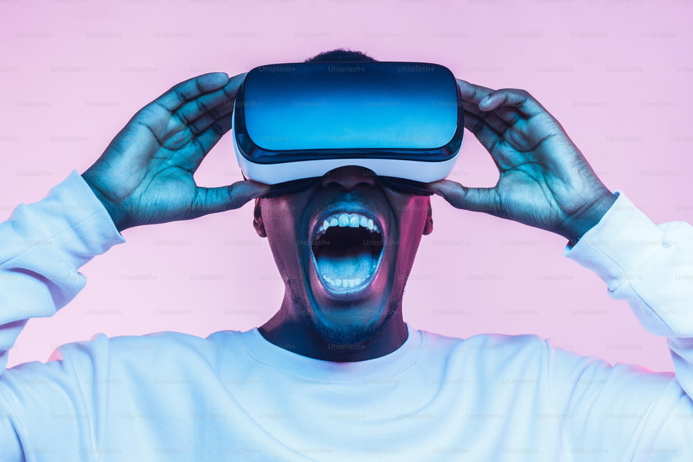 Emocionado hombre africano sorprendido viendo una película a través de gafas de realidad virtual, gritando
