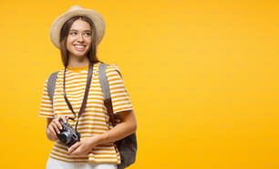 Bannière horizontale d’une jeune touriste souriante tenant une caméra, isolée sur fond jaune avec espace de copie