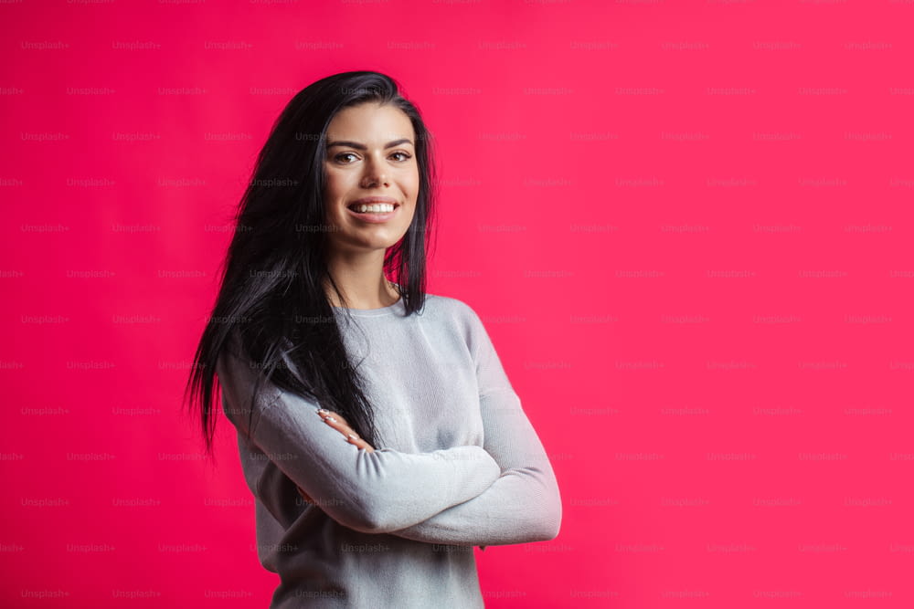 close up portrait of pleasant smiling model with long beautiful straight unbinding hair isolated on the pink background