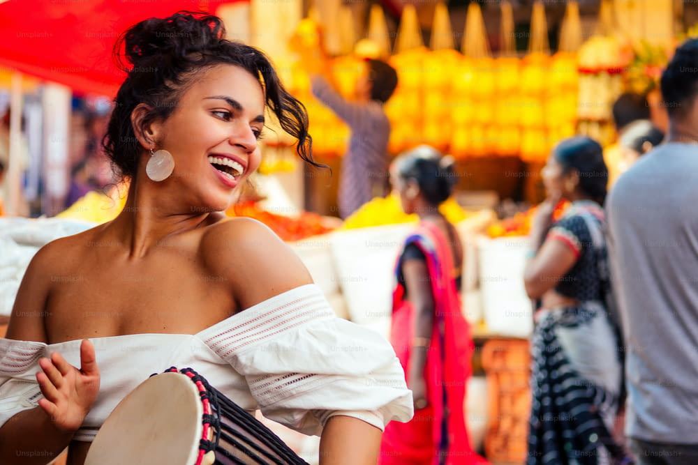 アジアのバザールでポーズをとるファッショナブルな服を着たインド人がジャンベ音楽ドラマーを演奏する。