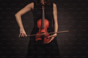 검은 배경에 바이올린을 연주하는 바이올리니스트 여자의 손