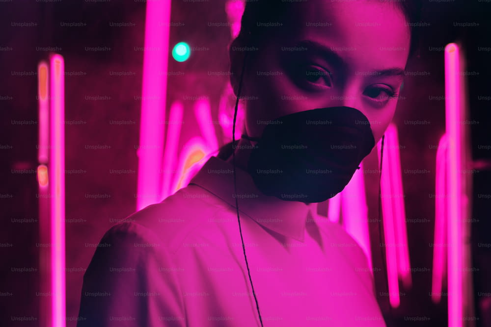Portrait of young asian teenage girl wearing mask in purple neon light. Cyber, futuristic, virus protection concept
