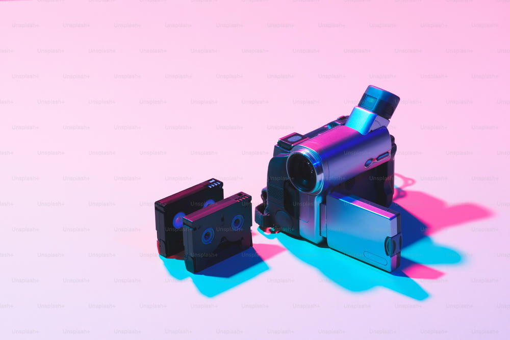 분홍색 배경에 배열된 비디오 카세트와 디지털 비디오 카메라의 클로즈업 보기