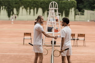 복고풍 스타일의 테니스 선수들이 코트에서 테니스 네트 위에서 악수하는 모습