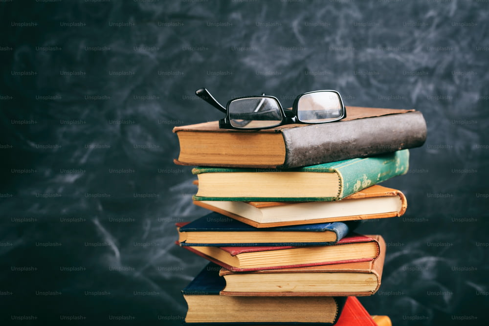 �教育のコンセプト。黒板の背景に古い本と眼鏡