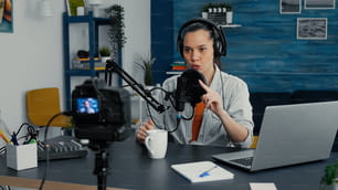 Famous social media influencer greeting internet public while starting to record daily vlog. Attractive digital content creator filming herself talking with audience while sitting at home studio desk.