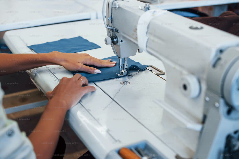 Vista dettagliata della donna sarta cuce vestiti sulla macchina da cucire in fabbrica.