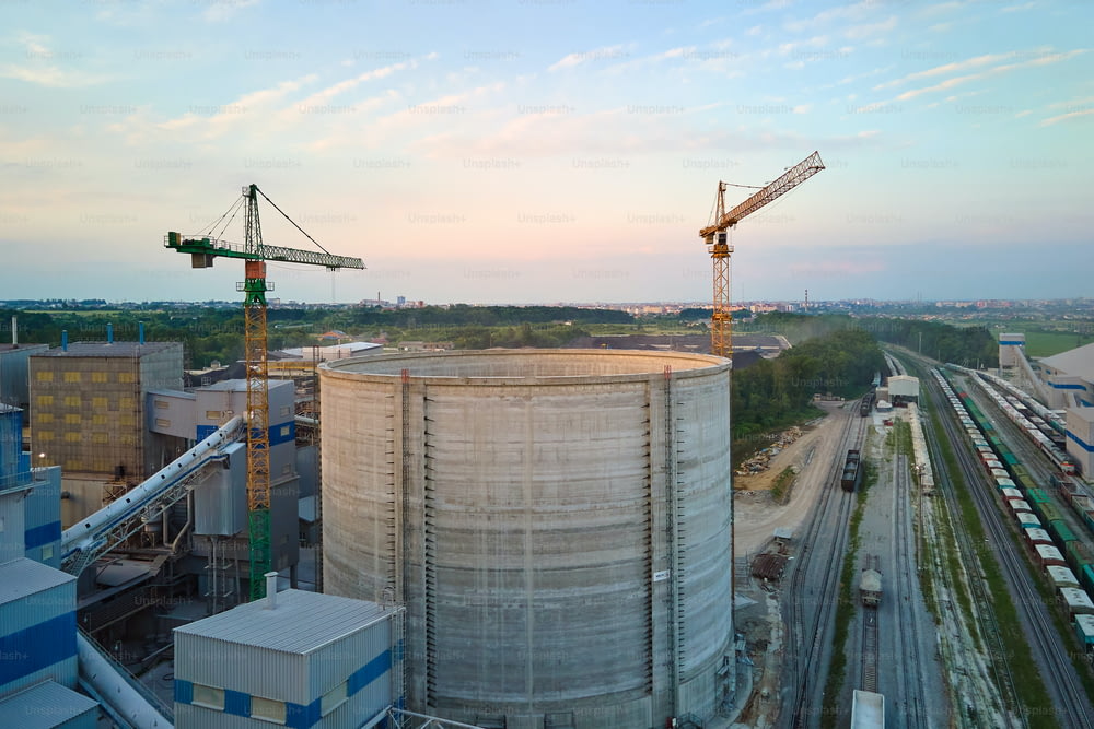Planta de cemento con estructura de alta fábrica y grúas torre en el área de producción industrial. Fabricación y concepto de industria global.