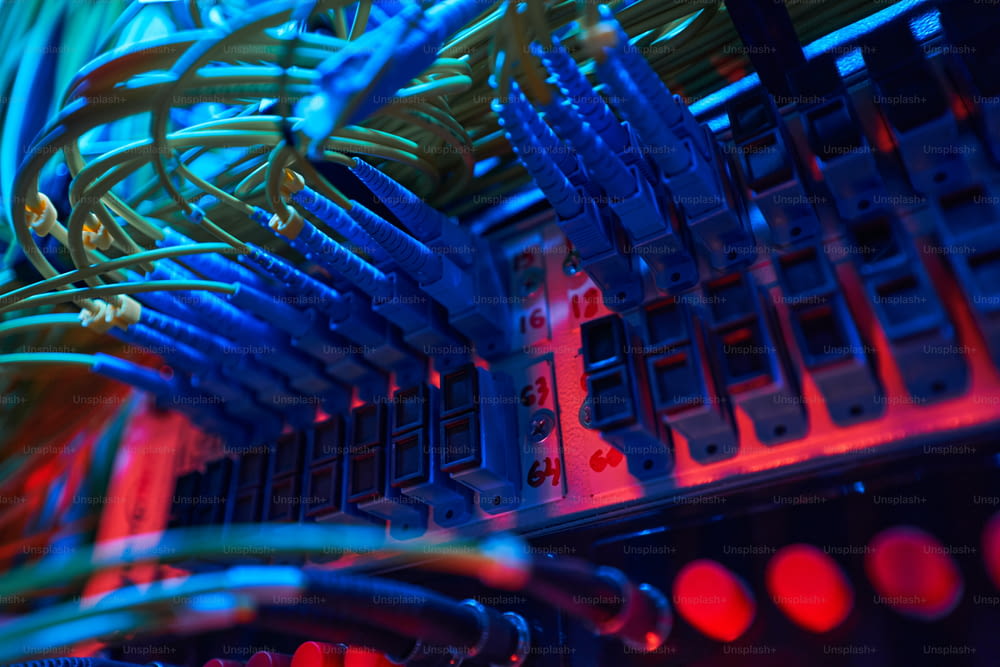 Blue optical fiber cables inserted into ports of switch panel inside server rack