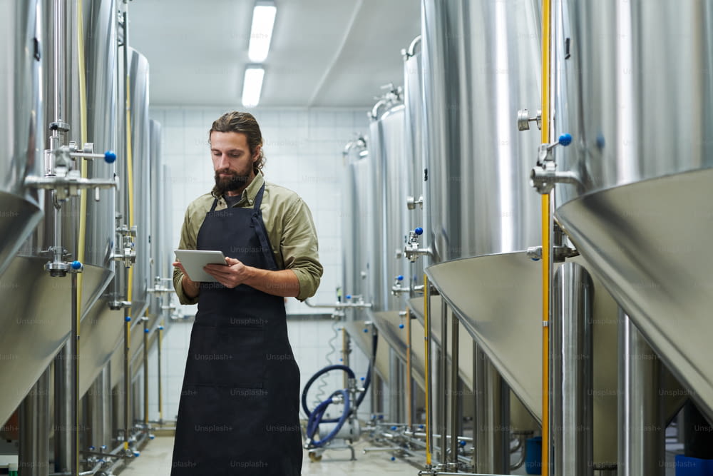 Manager controlling work of beer brewery via application on digital tablet