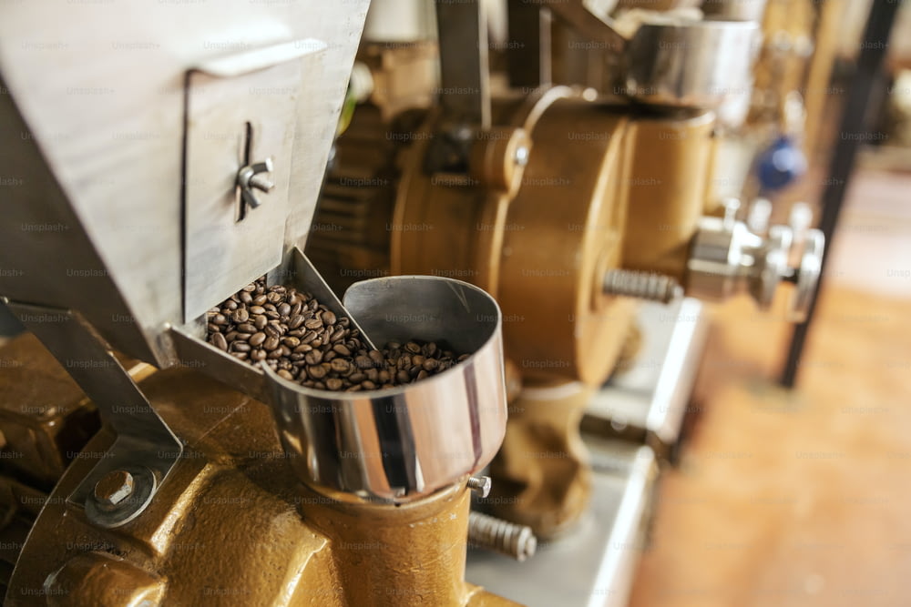Primo piano della macchina per macinare caffè con chicchi di caffè in fabbrica.
