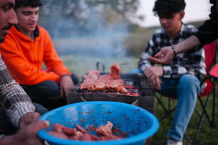 a group of people sitting around a bbq grill
