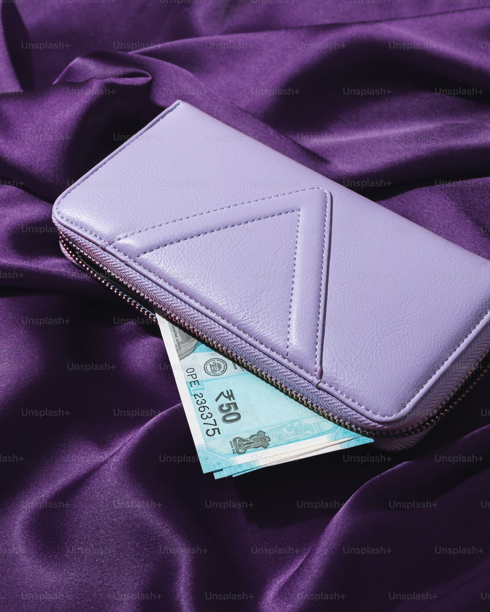 Una billetera púrpura encima de una tela púrpura