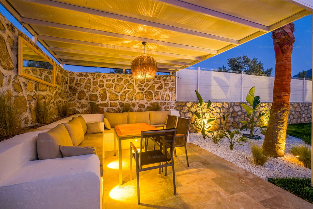 a patio with a table, couches and lights
