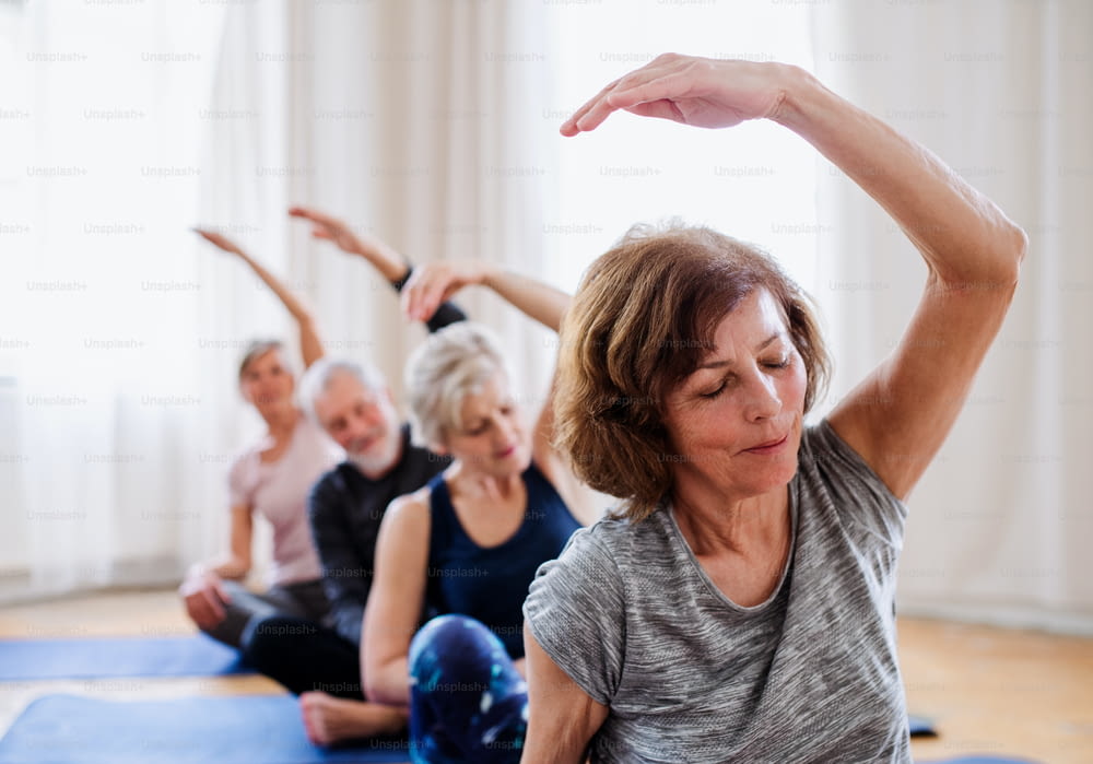 Groupe de personnes âgées actives faisant des exercices de yoga dans un club de centre communautaire.