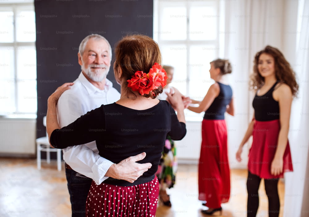 A group of senior people attending dancing class with dance teacher.